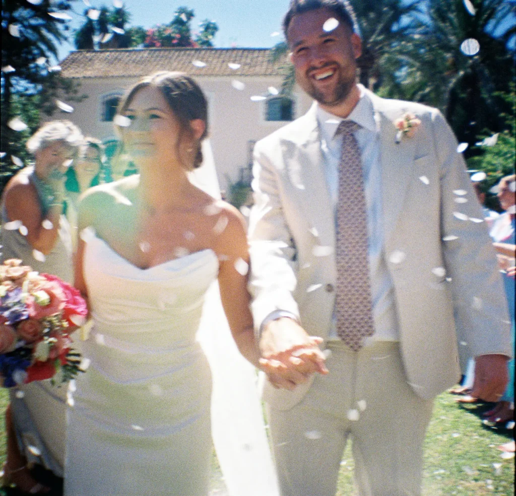 Couple walking through falling petals after the ceremony