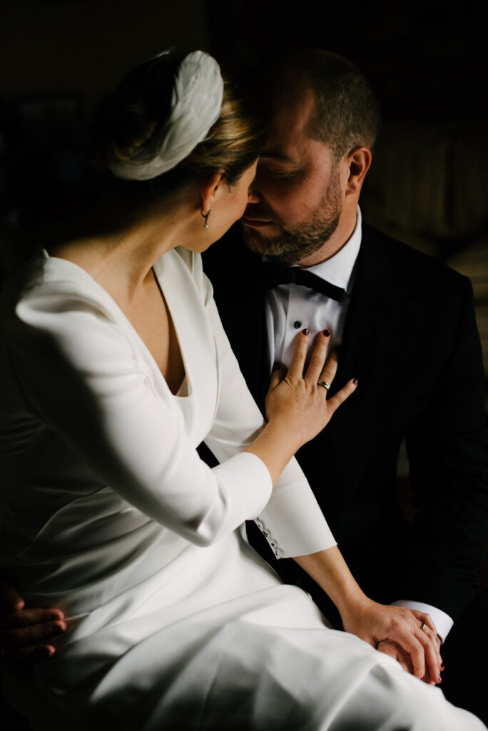 Bride resting her hand on the groom's chest in soft low light at a palace house in Jerez