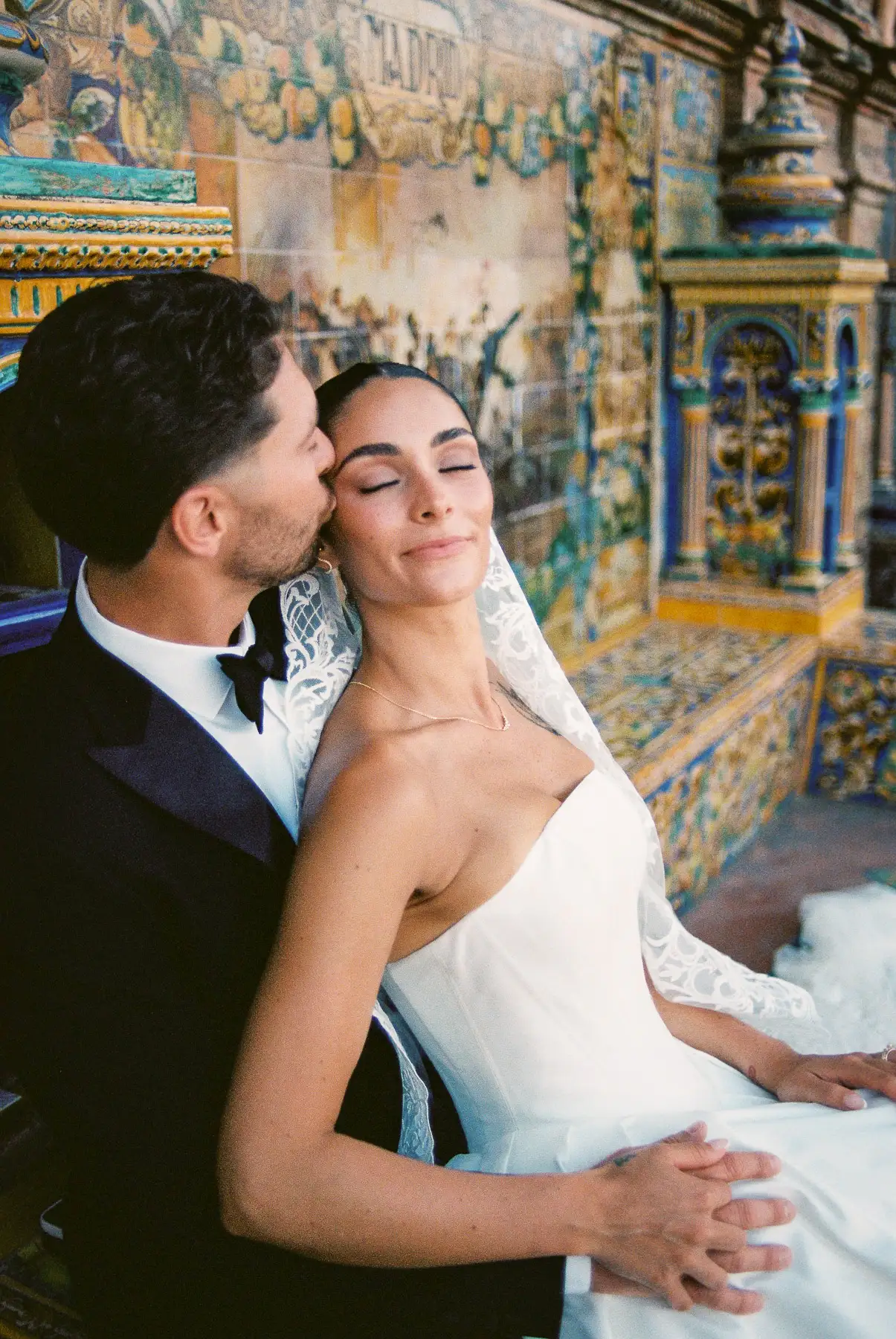 Couple at Plaza de España in Seville, he kisses her temple as she closes her eyes, shot on film
